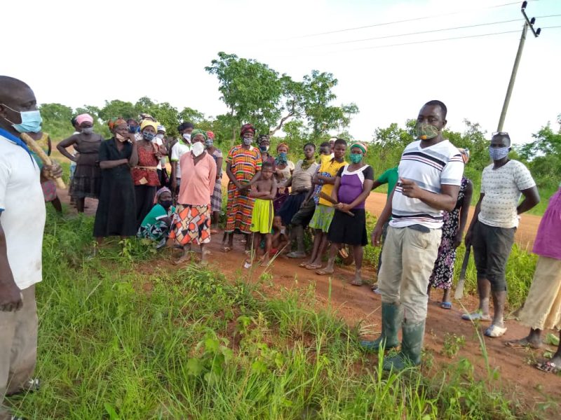 Extension agent leading a group discussion with farmers beside a field